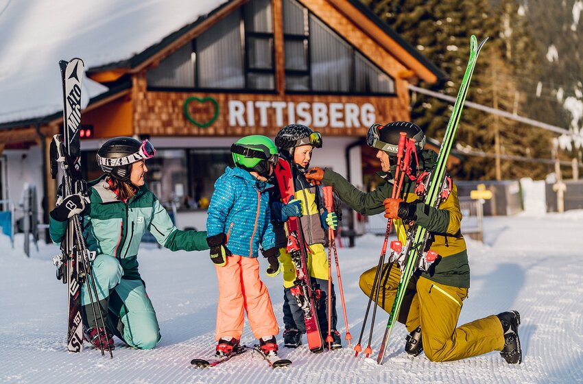 Ski family getting ready for a ski day at Rittisberg | © Rittis-Lift Engelhardt GmbH & Co KG Two adults and two kids with ski gear prepare for their ski day in front of the Rittisberg building. | © Rittis-Lift Engelhardt GmbH & Co KG