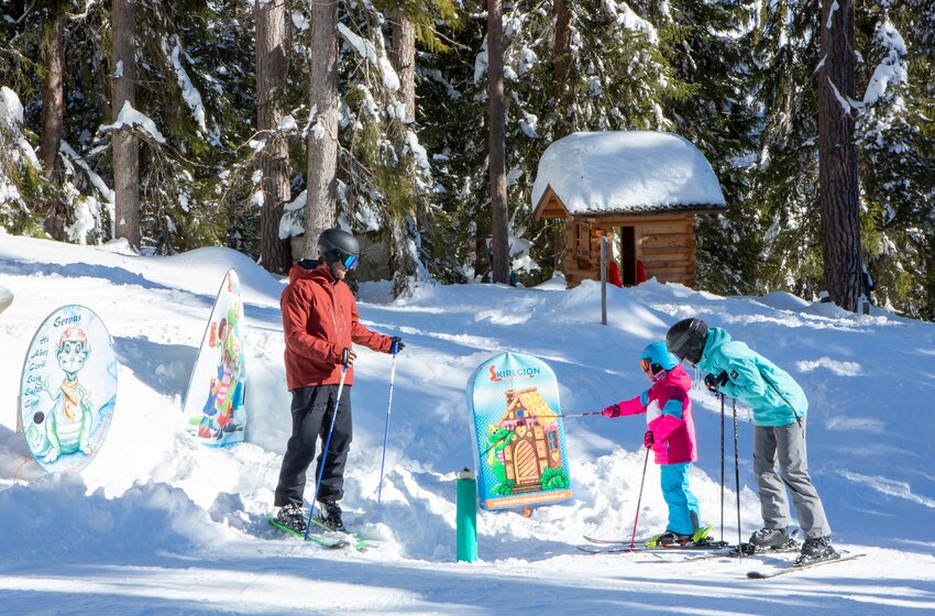 Child points at a fairy tale station on the ski trail, joined by two adults in the snowy woods at Rittisberg. | © Rittis-Lift Engelhardt GmbH & Co KG